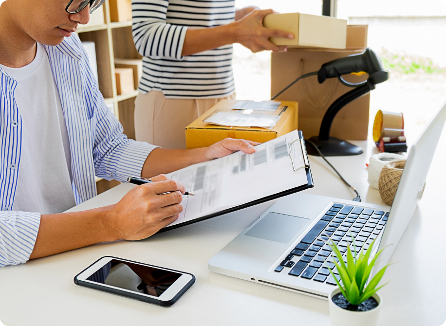 Person checking logistics paperwork near a laptop